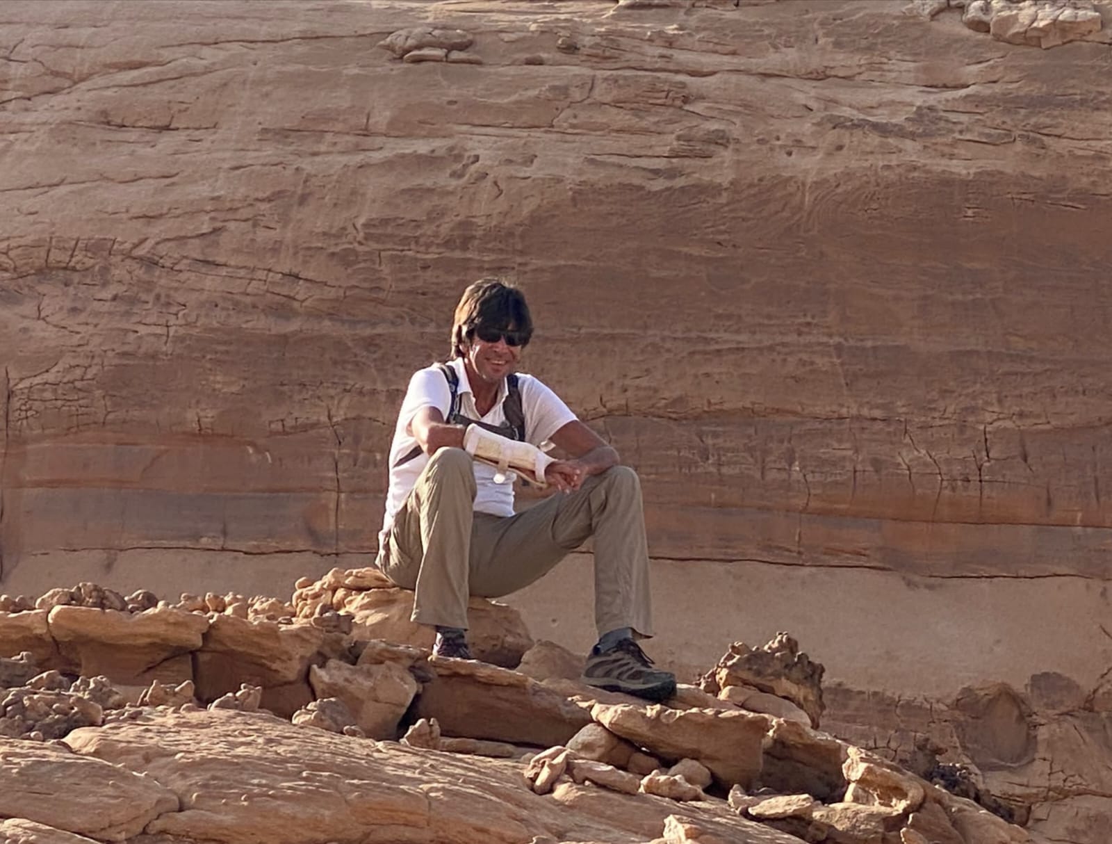 Alain assis sur un rocher de grès rouge dans le désert égyptien